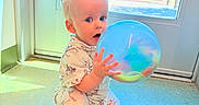 Sunnie joined the competition — help win amazing prizes! ball, blue, child, clothing, curious, daylight, door, expression, floor, indoor, light, person, playground, shadow, shoe, squatting, toddler, toy, window, young_child