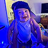 baby, child, infant, smiling, happy, portrait, cap, hat, being_held, adult_hands, indoor, living_room, television, dresser, toy, blue_lighting, clothing, playful, close_up, photography