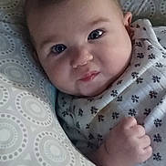 River is registered to the contest to win money with this photo: baby, infant, face, pillow, patterned_pillow, cute, expression, hand, fist, lying_down, bed, blanket, sleepwear, indoors, child, portrait, young, soft_lighting, closeup, resting