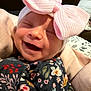 baby, smiling, pink_bow, hat, floral_clothing, blanket, infant, cute, happy, face, portrait, child, soft_texture, cozy, indoor, newborn, wrapped, headwear, person, closeup