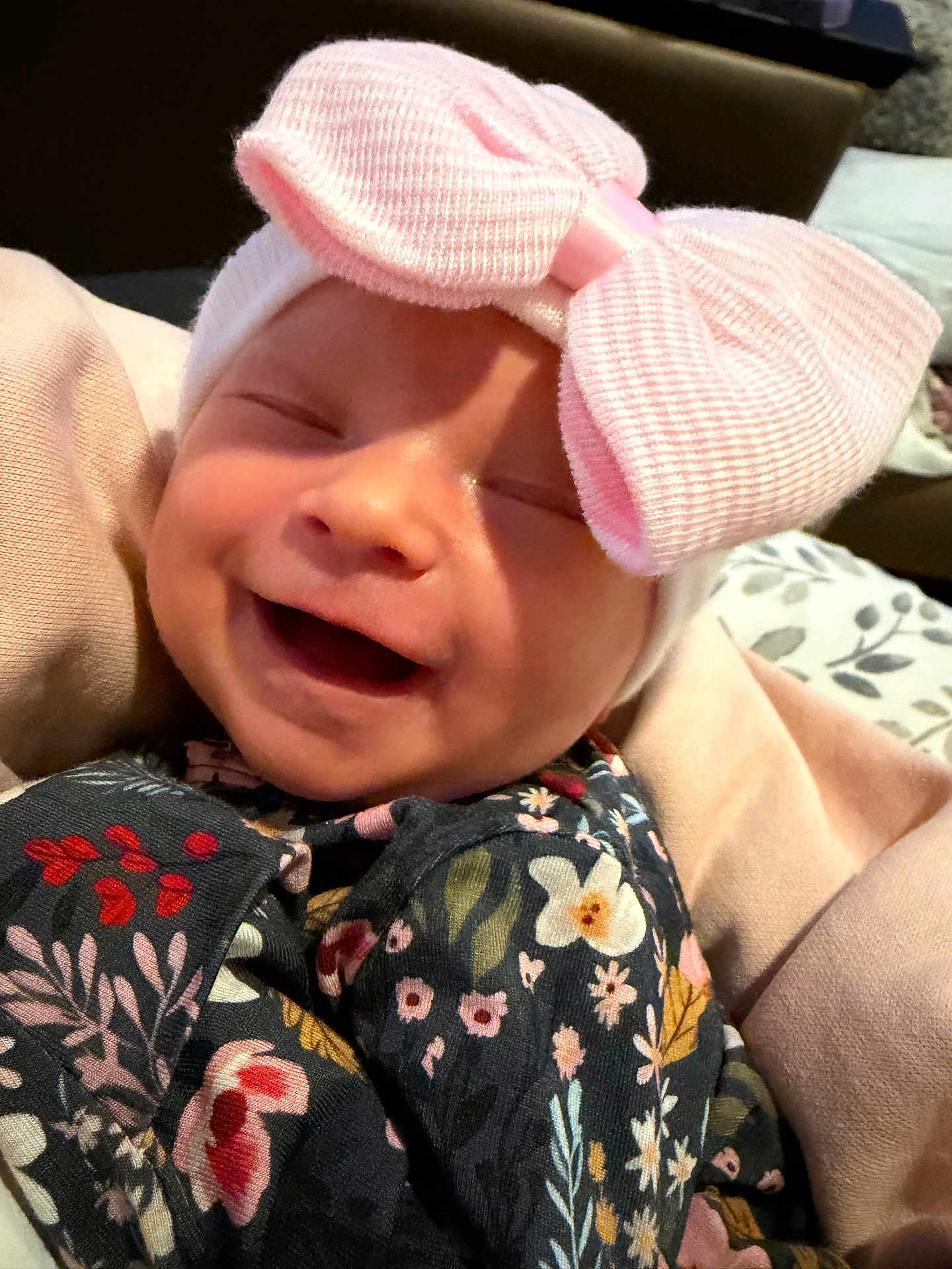 Everlee is registered to the contest to win money with this photo: baby, smiling, pink_bow, hat, floral_clothing, blanket, infant, cute, happy, face, portrait, child, soft_texture, cozy, indoor, newborn, wrapped, headwear, person, closeup