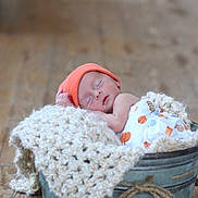 Harlan joined the competition — help win amazing prizes! newborn, baby, sleeping, orange_hat, blanket, metal_bucket, wooden_floor, cozy, infant, soft_light, knit_blanket, peaceful, wrapped, cute, indoors, portrait, resting, small, child, baby_clothes