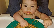 Alexander joined the competition — help win amazing prizes! baby, child, high_chair, eating, food, rice, noodles, plate, messy, smiling, face, hands, indoor, portrait, sitting, dinner, meal, feeding, infant, home
