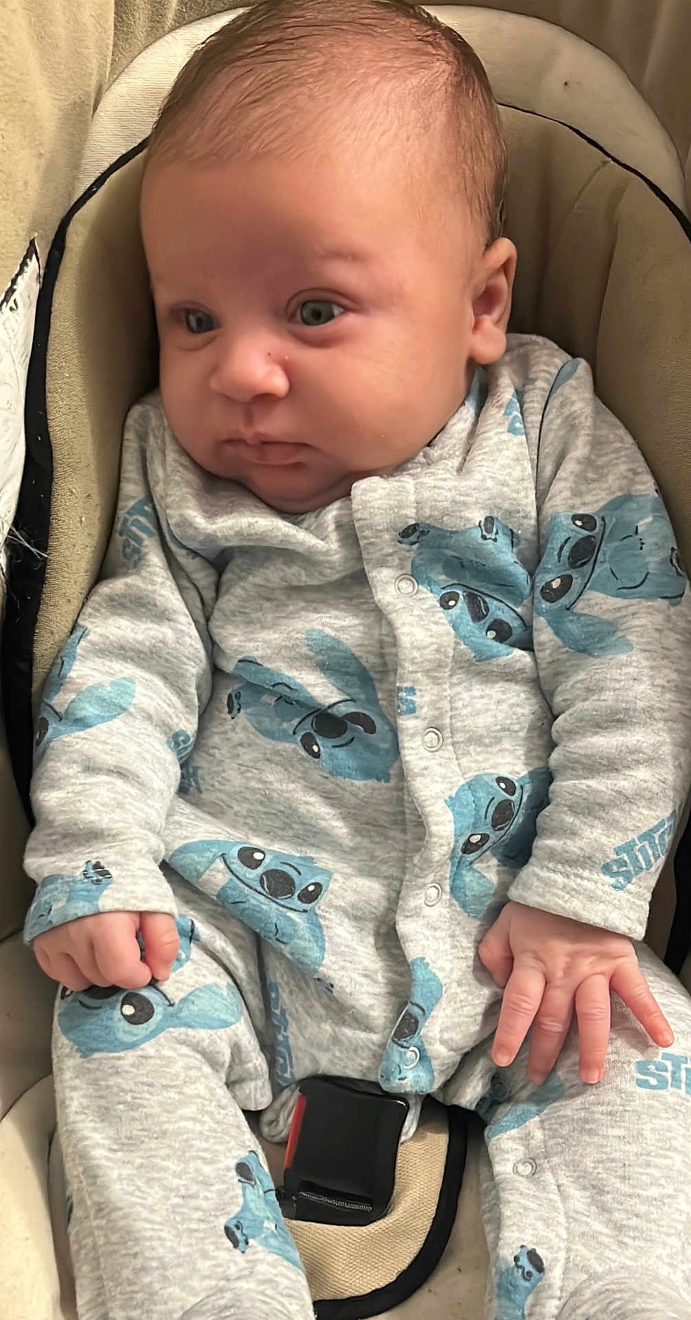 Samy participe au concours pour gagner de l'argent avec cette photo : baby, infant, car_seat, onesie, clothing, blue, grey, hands, face, eyes, seatbelt, child, cute, young, sitting, indoor, portrait, soft, expression, newborn