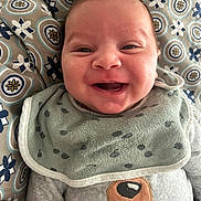 Samy a rejoint le concours — aidez-le/la à gagner de superbes lots ! baby, smile, face, bib, clothing, patterned_blanket, happy, infant, cute, portrait, child, apparel, fabric, textile, human, closeup, head, lying_down, soft, cozy