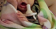 Ila is registered to the contest to win money with this photo: adult, baby, bed, blanket, cozy, eyes_closed, face, home, indoors, infant, newborn, pacifier, pastel, portrait, rubbing_eye, sitting, sleeping, striped_blanket, swaddled, yawning
