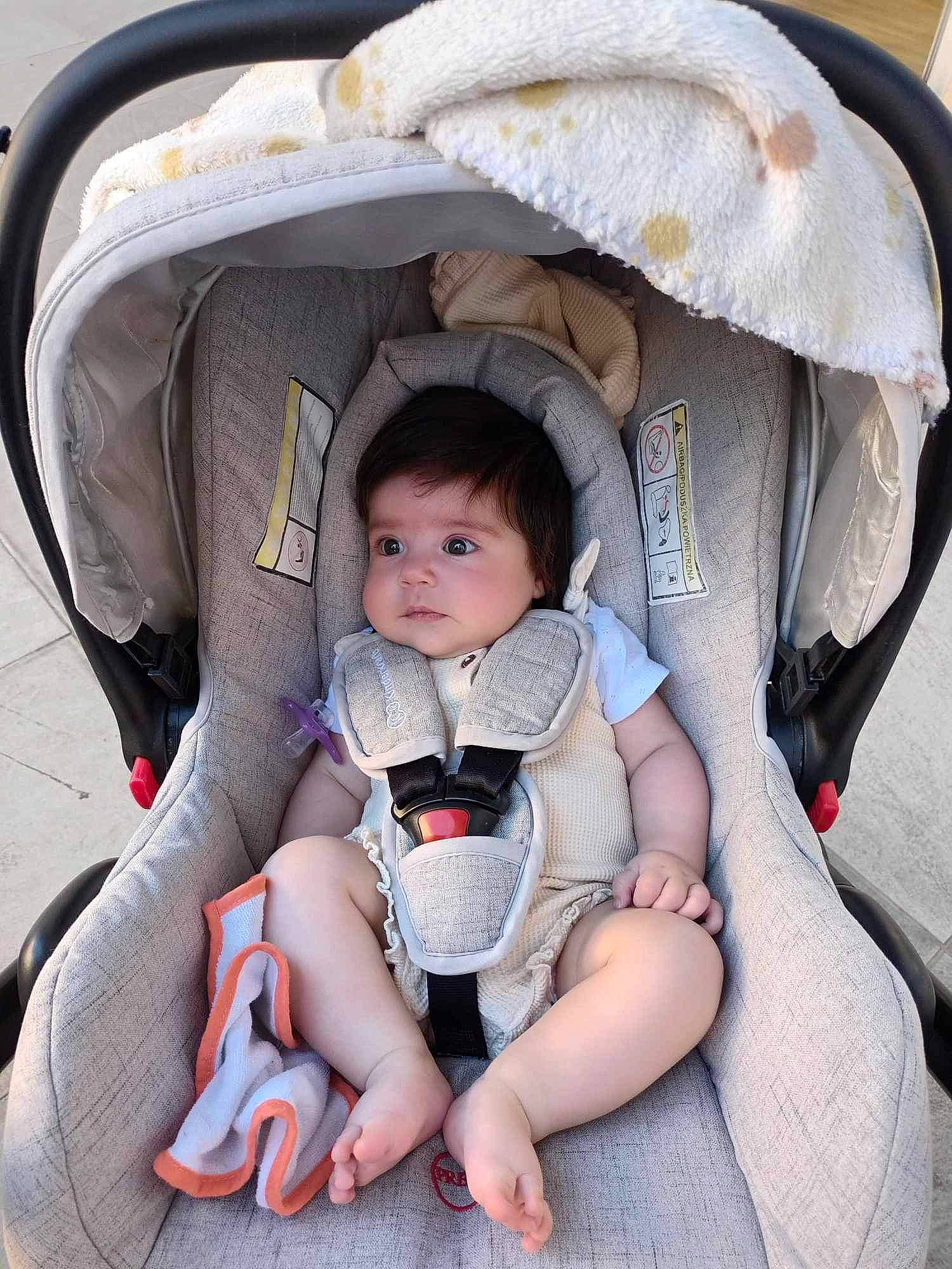 Mya a rejoint le concours — aidez-le/la à gagner de superbes lots ! auto_part, baby, baby_carriage, baby_in_car_seat, baby_products, baby_safety, baby_toddler_clothing, car_seat, carmine, child, comfort, fun, lap, leg, person, personal_protective_equipment, sitting, thigh, thumb, toddler