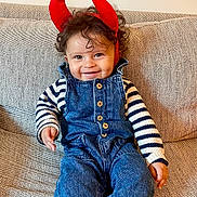 Ava participe au concours pour gagner de l'argent avec cette photo : baby_toothbrush, casual_clothing, child, couch, cozy, curly_hair, cute, denim_overalls, face, happy, indoor, infant, playful, portrait, red_horns, seated, smiling, socks, striped_sweater, toddler