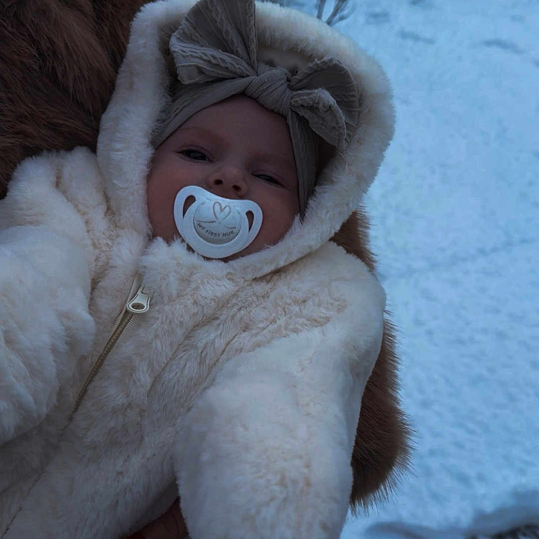 Tiyanna a rejoint le concours — aidez-le/la à gagner de superbes lots ! baby, bow, child, cold, cute, face, fur, fur_coat, hand, headband, nail_polish, onesie, outdoor, pacifier, person, portrait, snow, warm_clothing, winter, winter_clothing