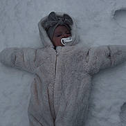 Tiyanna a rejoint le concours — aidez-le/la à gagner de superbes lots ! baby, snow, winter_clothing, onesie, pacifier, headband, bow, infant, outdoor, snow_angel, cold, cute, child, frozen, lying_down, fluffy, winter, peaceful, face, snowy_background