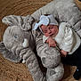 Tiyanna a rejoint le concours — aidez-le/la à gagner de superbes lots ! baby, sleeping, headband, bow, plush_toy, elephant, rug, floor, white_clothing, black_pants, soft_texture, child, indoors, peaceful, cute, infant, resting, cozy, toy, nap