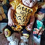 Raina-Lynn is registered to the contest to win money with this photo: baby, child, smiling, yellow_shirt, sunflower_pants, headband, flower_headband, booties, socks, blanket, animated_characters, lion_faces, cute, seated, indoors, happy, portrait, colorful, clothing, infant