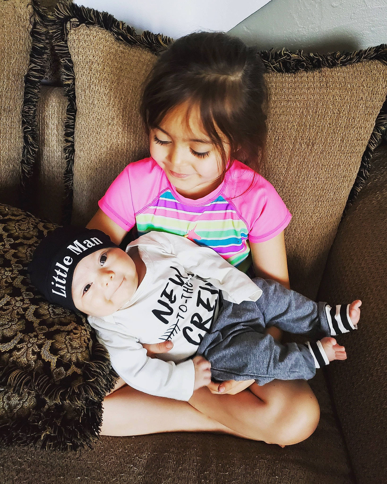 Ambrose is registered to the contest to win money with this photo: arm, baby, black_hair, child, ear, happy, headwear, leg, person, pink, play, sitting, skin, sleeve, smile, t_shirt, thigh, toddler, top, trunk