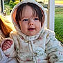 baby, child, hooded_jacket, outdoor, sunlight, smiling, face, person, cute, infant, warm_clothing, nature, portrait, young_child, hand, grass, daylight, suburban, casual, happy