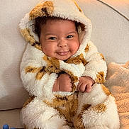 Raian is registered to the contest to win money with this photo: baby, infant, smile, hooded_clothing, fluffy, couch, cozy, warm_lighting, cute, child, indoors, soft_texture, happy, portrait, sitting, fuzzy, clothing, hands, feet, face