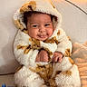 baby, infant, smile, hooded_clothing, fluffy, couch, cozy, warm_lighting, cute, child, indoors, soft_texture, happy, portrait, sitting, fuzzy, clothing, hands, feet, face