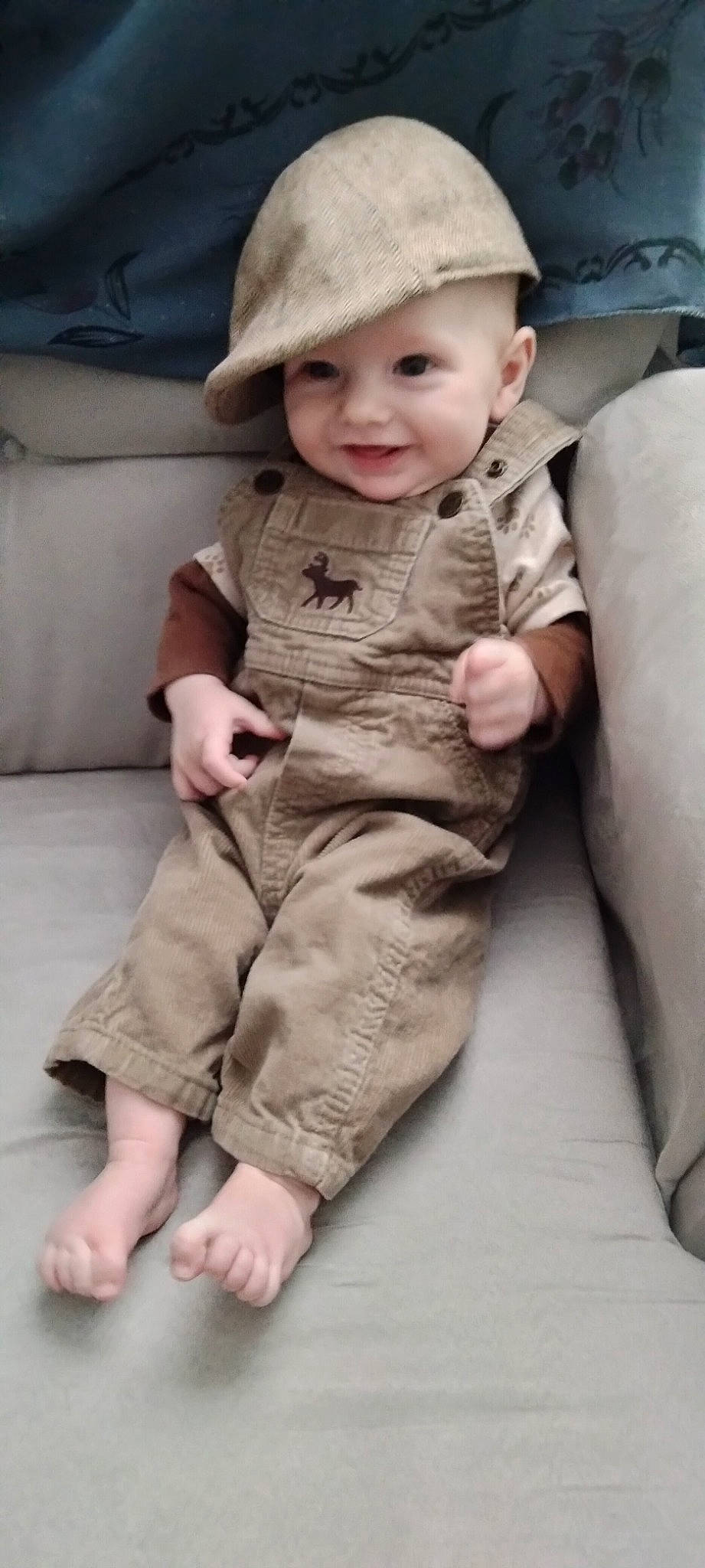 Maddox is registered to the contest to win money with this photo: baby, baby_toddler_clothing, barefoot, cheek, child, comfort, floor, flooring, foot, hat, headwear, human_leg, joy, linens, pattern, person, sitting, skin, sleeve, smile