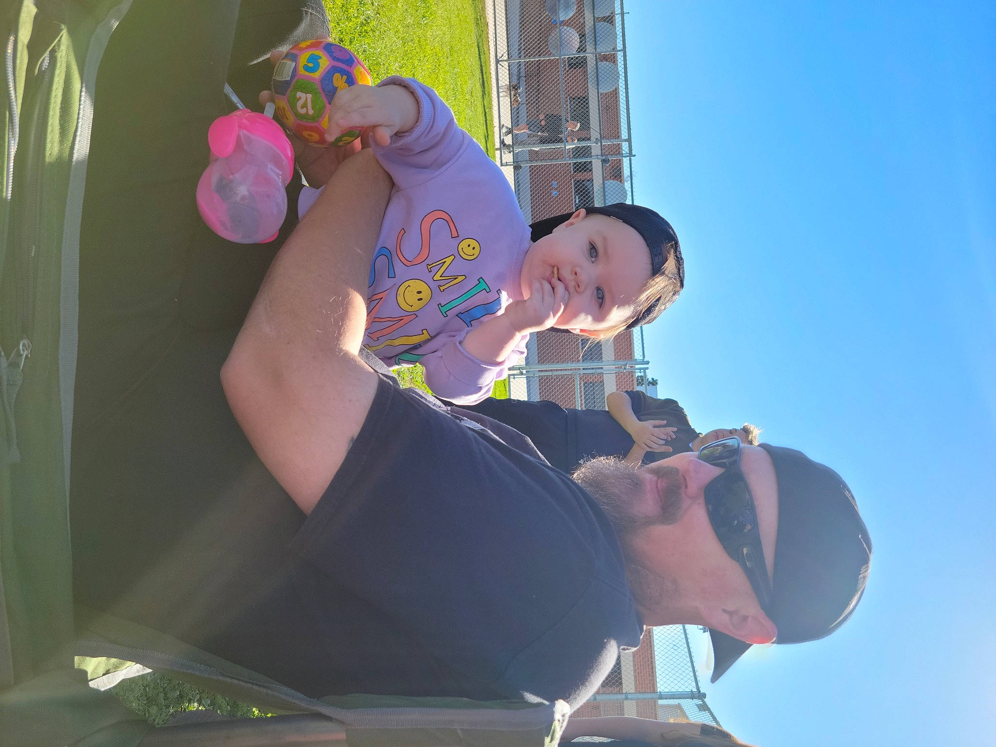 Ryan is registered to the contest to win money with this photo: elbow, eyewear, fun, gesture, grass, happy, hat, headwear, leisure, person, recreation, sitting, sky, smile, t_shirt, vacation