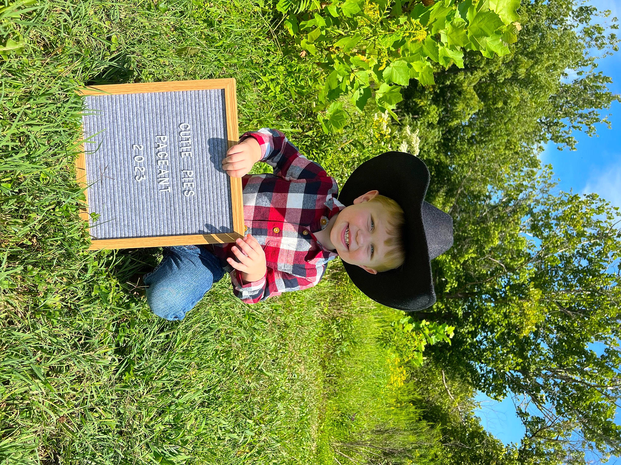 Carter joined the competition — help win amazing prizes! fun, garden, grass, grass_family, grassland, groundcover, happy, hat, joy, landscape, lawn, leaf, leisure, people_in_nature, person, plant, shrub, sitting, sky, smile