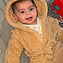 baby, child, hooded_coat, teddy_bear, smiling, happy, indoor, play_mat, toy, colorful, face, infant, cute, warm_clothing, person, young_child, cozy, childcare, baby_girl_or_boy, soft_texture