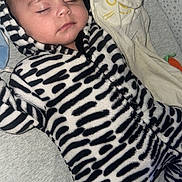 Inaya participe au concours pour gagner de l'argent avec cette photo : baby, sleeping, onesie, zebra_stripes, plush_toy, soft_texture, cozy, infant, child, cute, peaceful, face, closed_eyes, headwear, indoor, blanket, bed, pattern, young, resting