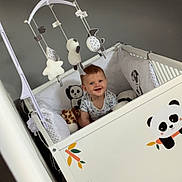 Raphaël participe au concours pour gagner de l'argent avec cette photo : baby, crib, panda, toy, mobile, smile, red_hair, white, gray_wall, plush, infant, cute, child, furniture, decor, indoor, happy, sitting, person, room