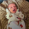 Blake is registered to the contest to win money with this photo: baby, blanket, close_up, clothing, cozy, eyes, face, hospital, indoors, infant, lying_down, medical_equipment, nasal_tube, newborn, onesie, open_mouth, patterned_fabric, portrait, sleeping_area, swaddle