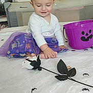 Juliana a rejoint le concours — aidez-le/la à gagner de superbes lots ! baby, child, purple_skirt, headband, ears, toy_spiders, halloween_bucket, bedspread, room, curious, sitting, foot, white_clothing, indoor, playful, decorations, toys, smiling, cute, costume