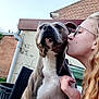 dog, person, outdoor, kiss, glasses, brick_wall, chair, fence, sky, pet, love, affection, animal, canine, human, casual, daylight, portrait, friendly, happy