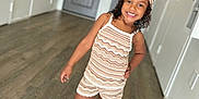 Devyn joined the competition — help win amazing prizes! casual_clothing, child, curly_hair, cute, door, floor, girl, hallway, happy, headband, indoor, knitted_outfit, person, pose, sandals, shorts, smiling, socks, standing, wooden_floor