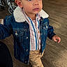 Adriel is registered to the contest to win money with this photo: big_eyes, boots, candid, casual_clothing, child, curious, curly_hair, denim_jacket, floor, furniture, indoor, pants, person, standing, striped_shirt, toddler, warm_clothing, wheelchair, wooden_floor, young_child