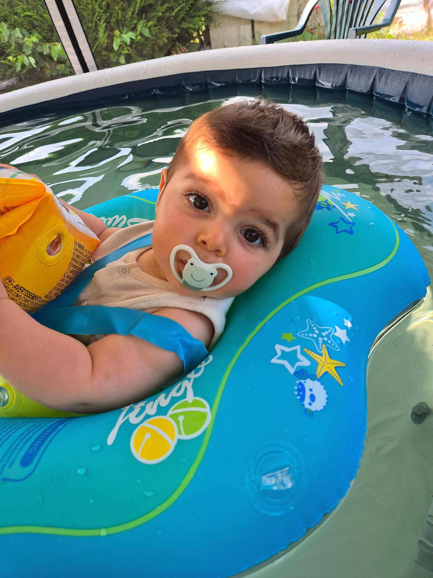 Loann participe au concours pour gagner de l'argent avec cette photo : baby, blue, child, face, float, infant, inflatable_ring, outdoor, pacifier, person, play, pool, relaxation, starfish, summer, sunlight, water, water_toy, yellow, young_child