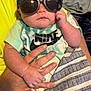Dallas Ray Jr. is registered to the contest to win money with this photo: baby, sunglasses, hand, clothing, tshirt, nike, tie_dye, person, infant, fashion, accessory, skin, blanket, fabric, indoor, portrait, cute, cool, holding, child