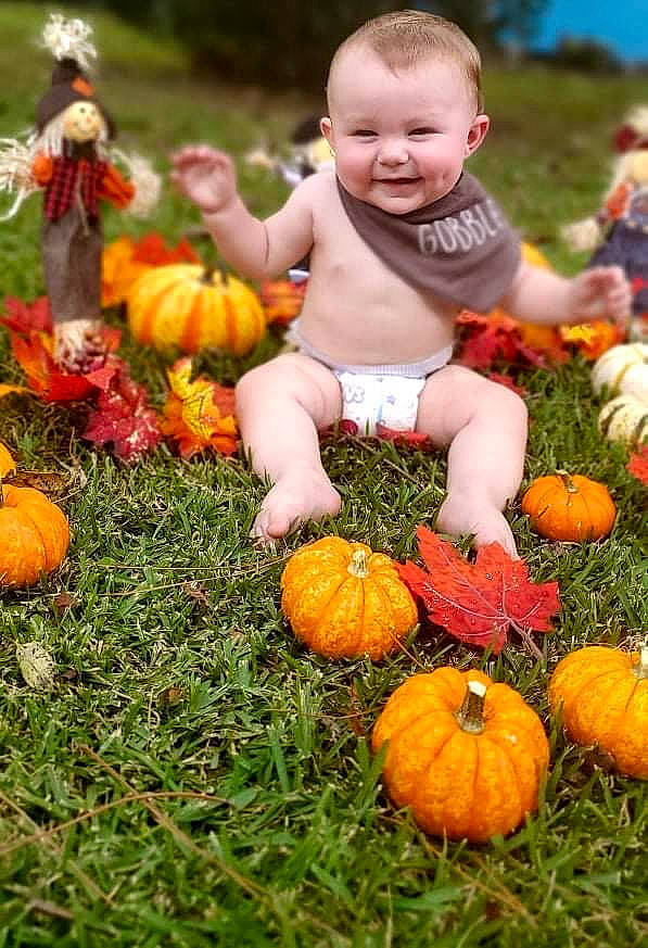 Parker is registered to the contest to win money with this photo: botany, calabaza, cucurbita, facial_expression, gourd, grass, green, happy, joy, leaf, natural_foods, nature, orange, people_in_nature, person, photograph, plant, pumpkin, smile, squash