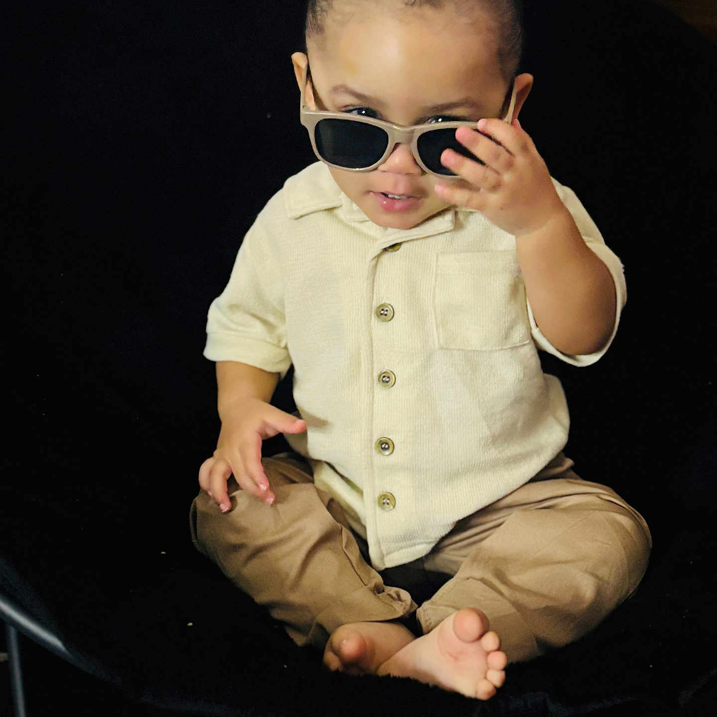Ezra is registered to the contest to win money with this photo: accessories, baby, bodypart, clothing, couch, face, finger, furniture, glasses, goggles, hand, happy, head, pants, person, photography, portrait, sitting, smile, sunglasses