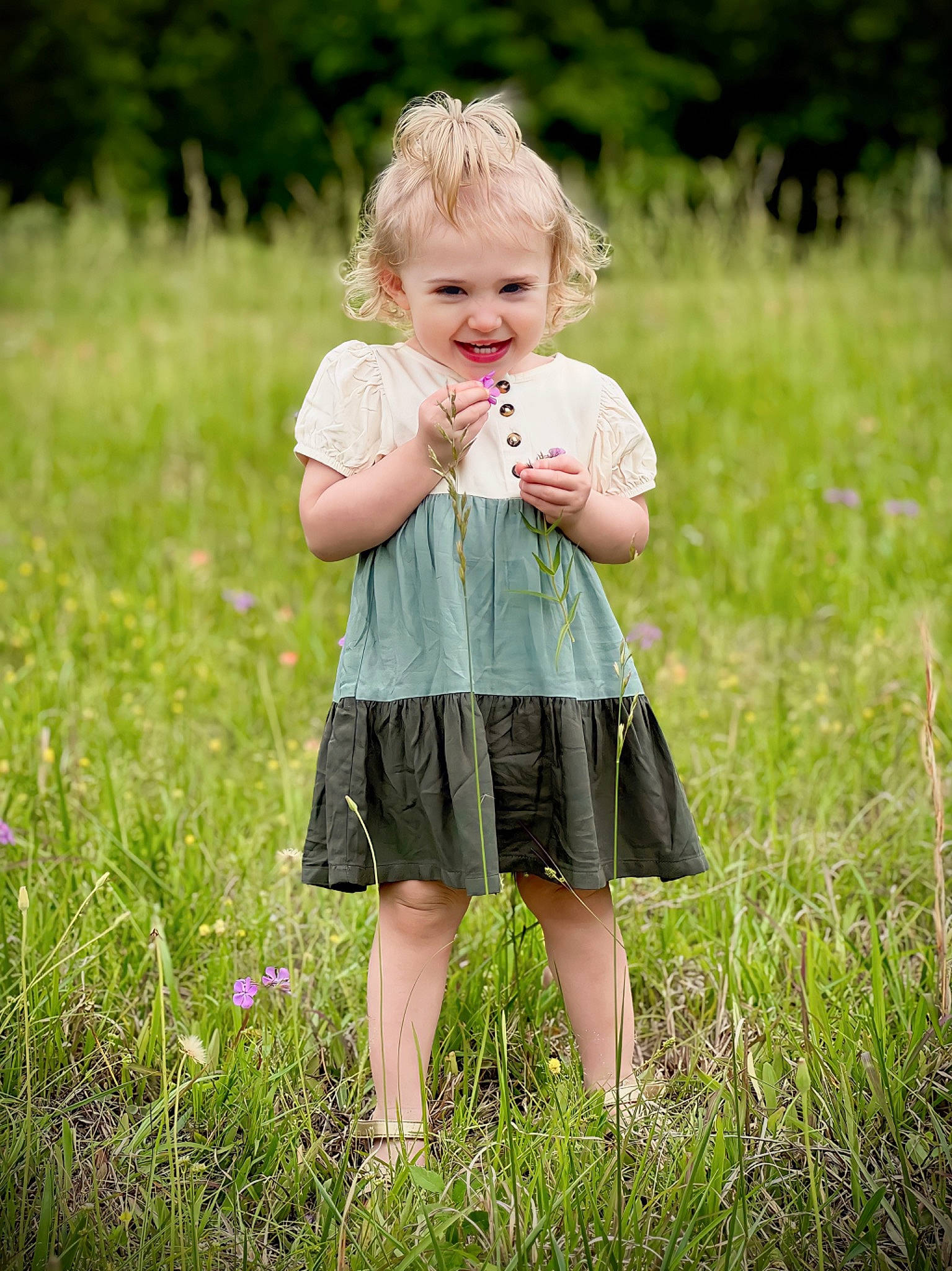 Olivia is registered to the contest to win money with this photo: baby, baby_toddler_clothing, blond, child, dress, field, flower, gesture, grass, grassland, happy, joy, meadow, pattern, people_in_nature, person, plant, prairie, sleeve, smile