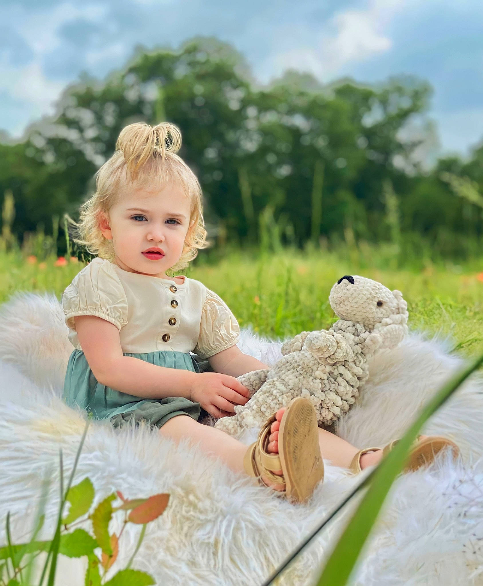 Olivia joined the competition — help win amazing prizes! baby, baby_toddler_clothing, cloud, dress, fawn, fun, grass, grassland, happy, meadow, peach, people_in_nature, person, plant, prairie, sitting, sky, stuffed_toy, toddler, toy