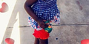 Londyn joined the competition — help win amazing prizes! child, girl, smiling, posing, sidewalk, outdoor, red_shorts, blue_top, sandals, hairband, curly_hair, sunlight, heart_graphics, playful, happy, person, summer, casual_clothing, concrete, shadow