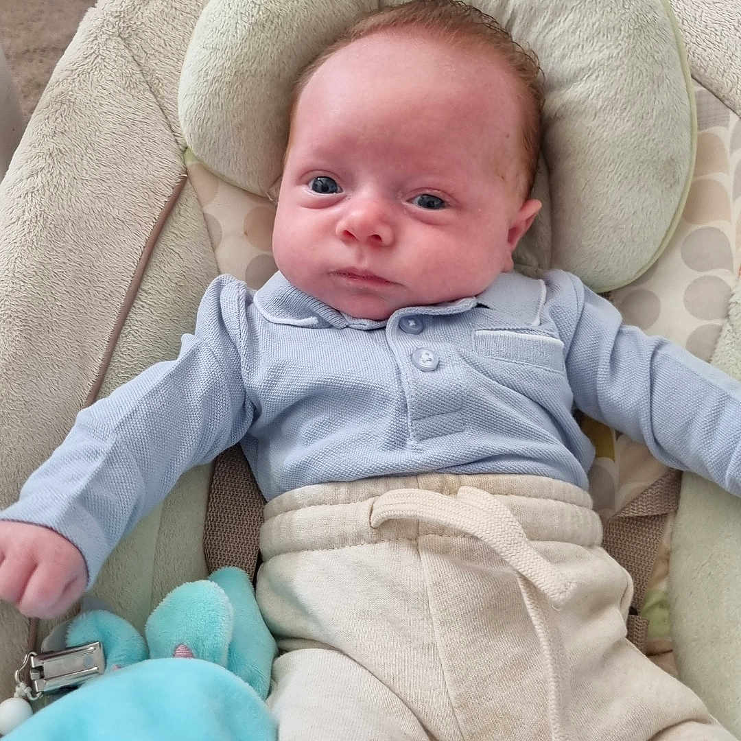 Layden a rejoint le concours — aidez-le/la à gagner de superbes lots ! baby, baby_chair, beige_pants, blue_clothing, calm_expression, child, comfort, curious_look, cushion, cute, home, indoor, infant, person, plush_toy, portrait, seated, soft_toy, wooden_floor, young_child