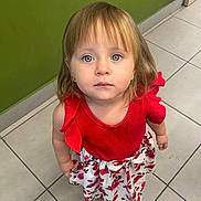 Nelya a rejoint le concours — aidez-le/la à gagner de superbes lots ! toddler, child, girl, red_top, floral_skirt, sandals, blue_eyes, standing, indoor, tile_floor, green_wall, curious, portrait, casual_clothing, short_hair, cute, innocent, person, looking_up, young_child