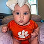 baby, infant, headband, bow, orange_onesie, cushion, purple, indoors, window, curious, face, blue_eyes, skin, hands, feet, soft_texture, person, child, portrait, cute