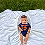 baby, infant, child, onesie, smile, grass, blanket, outdoor, greenery, cute, happy, sitting, footwearless, head, face, person, nature, young, casual_clothing, daylight