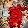 Aria joined the competition — help win amazing prizes! baby, infant, red_clothing, headband, christmas_ornaments, golden_balls, silver_balls, red_ball, string_lights, blanket, holiday_decor, festive, cute, portrait, indoors, soft_lighting, smiling, white_socks, toddler, holiday_theme