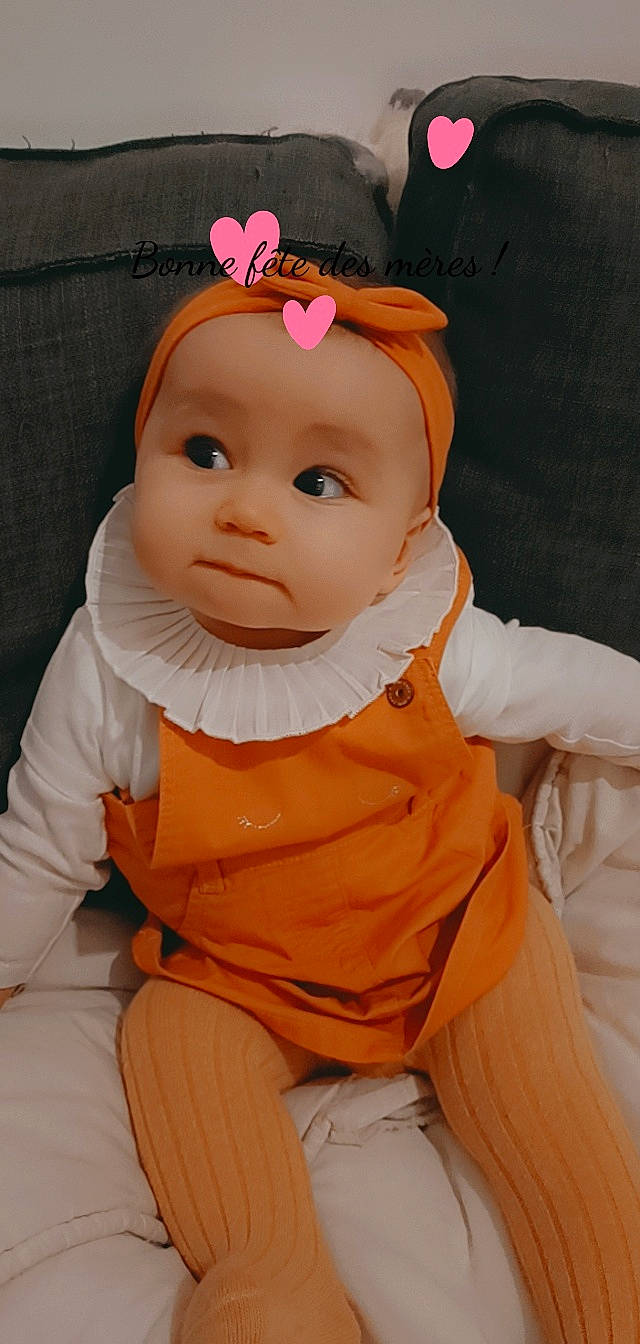 Sarah a rejoint le concours — aidez-le/la à gagner de superbes lots ! baby, baby_toddler_clothing, cap, cheek, child, costume_hat, doll, dress, eye, eyebrow, eyelash, iris, lip, nose, orange, outerwear, person, skin, sleeve, textile