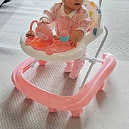 Maya participe au concours pour gagner de l'argent avec cette photo : toddler, baby_walker, pink_clothing, indoor, carpet, child, toy, walker, floor, curious, person, footwear, furniture, living_room, window, home, play, baby, standing, young_child