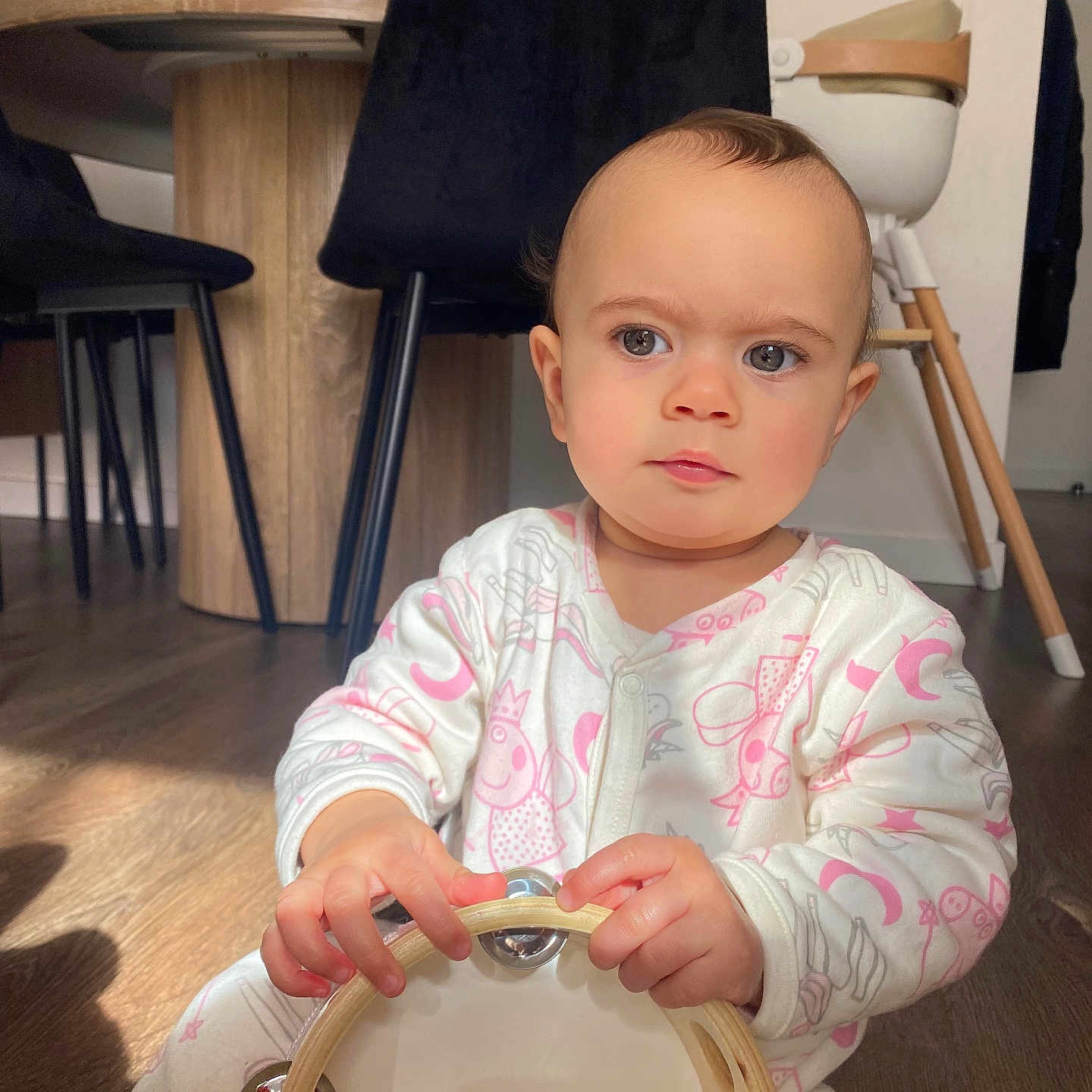 Eden participe au concours pour gagner de l'argent avec cette photo : baby, child, tambourine, pajamas, wooden_floor, sunlight, shadow, indoor, dining_chair, high_chair, playing, music_instrument, person, cute, expression, hands, flooring, furniture, home, young_child