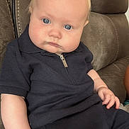 Tyde joined the competition — help win amazing prizes! baby, child, infant, blue_eyes, blonde_hair, navy_outfit, zipper, sitting, couch, leather_couch, curious, chubby_cheeks, indoor, portrait, casual_clothing, young_child, person, hand, face, expression