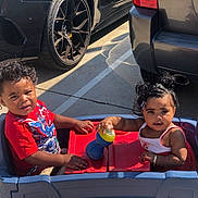 Karma joined the competition — help win amazing prizes! toddler, child, toy_wagon, parking_lot, car, sippy_cup, red_shirt, dress, sunlight, outdoor, curly_hair, playing, summer, cute, smiling, fun, two_children, casual, daytime, happy