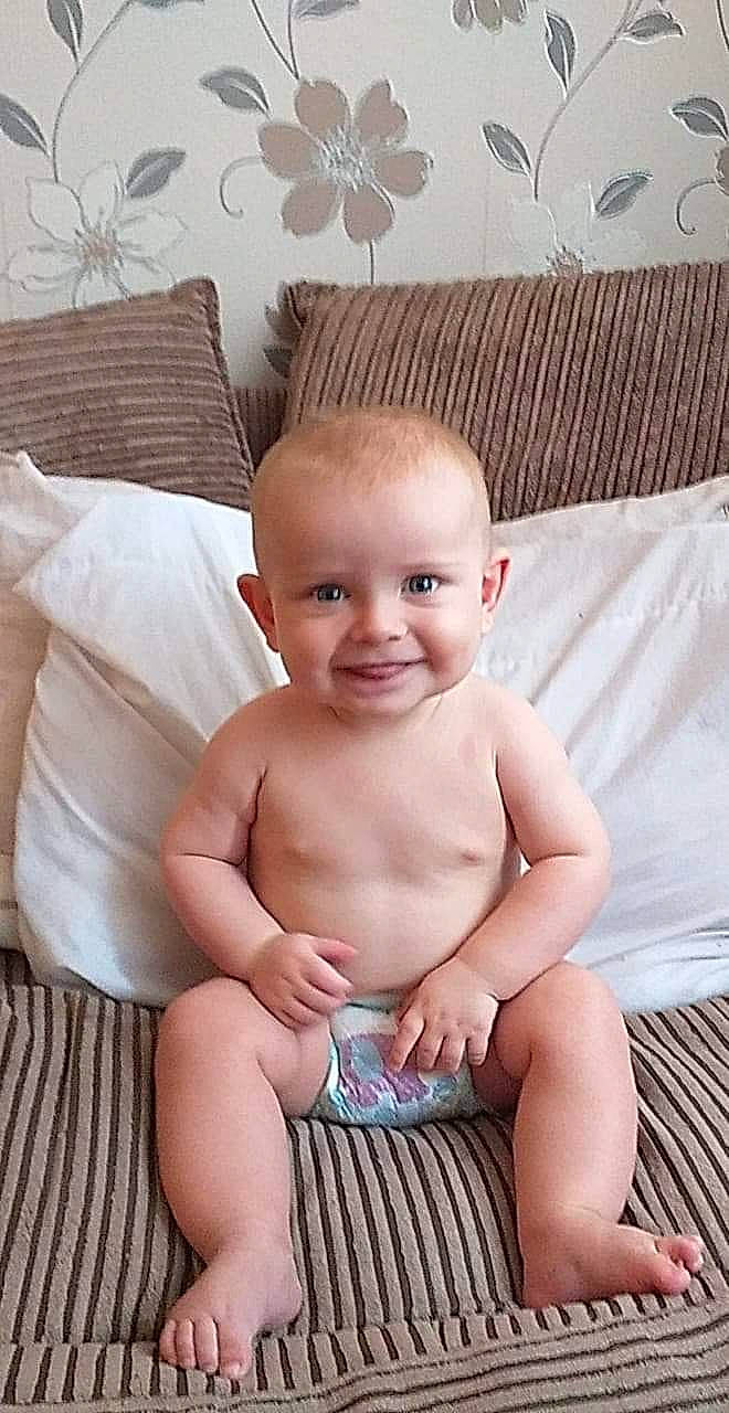 Stuart is registered to the contest to win money with this photo: baby, cheek, child, joy, leg, muscle, person, sitting, skin, smile, stomach, thumb, toddler