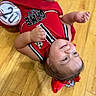 toddler, child, smiling, red_bow, cheerleading_outfit, wooden_floor, badge, happy, girl, indoor, cute, portrait, person, cheerleader, clothing, baby, fun, young_child, cheer, sport
